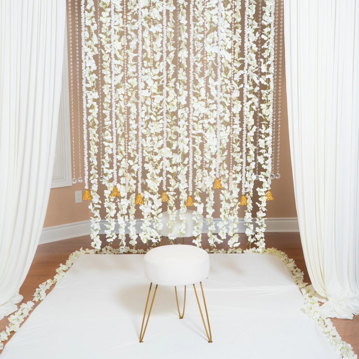 White blossom curtain backdrop with gold bells from a mehndi decor rental package in Scarborough