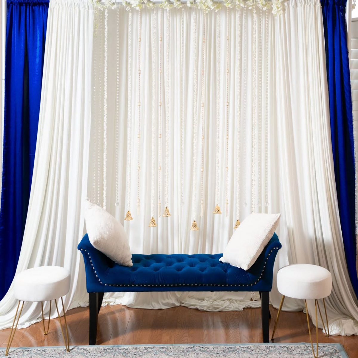 Indian wedding decor rental — royal blue velvet bridal seat with ivory drapes and gold bells, GTA