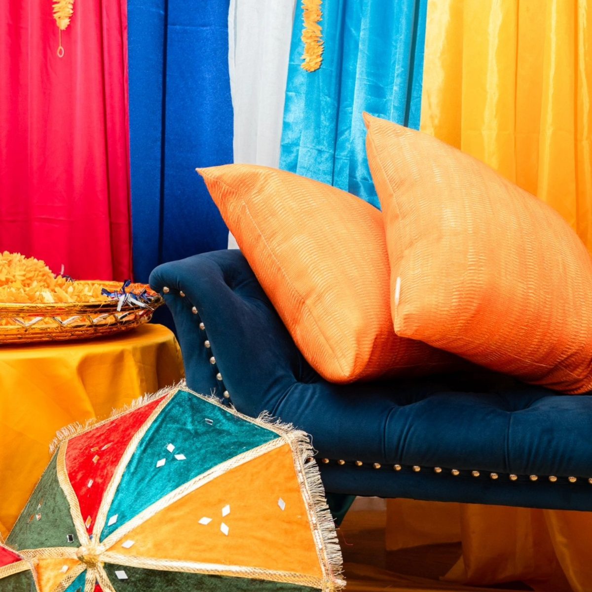 Mehndi stage detail with orange cushions, embroidered umbrella and marigold tray — Indian wedding decor Toronto
