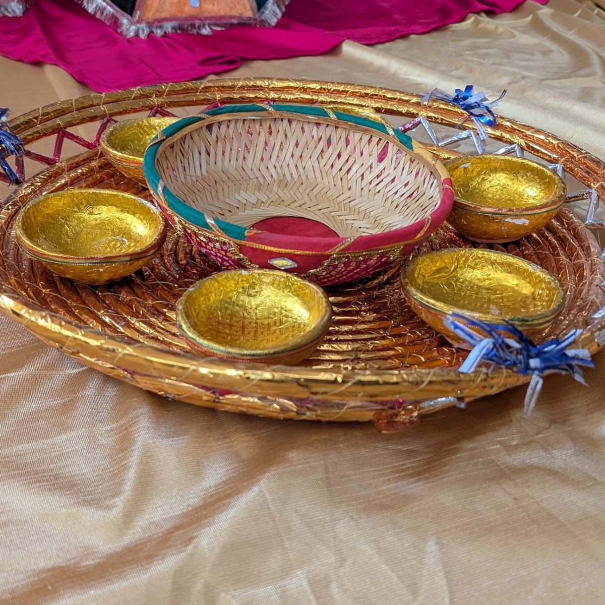 The Mehndi Thaali — close-up of a traditional woven mehndi thaali with small gold bowls and a woven basket, included with Toronto mehndi decor rentals
